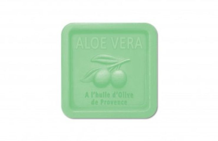 Mydło „mydlo_prowansalskie_bio_aloes-featured” to zielona, kwadratowa kostka z wytłoczonymi napisami „ALOE VERA” i „A l'huile d’Olive de Provence”, a także wzorem gałązki oliwnej pośrodku na białym tle.